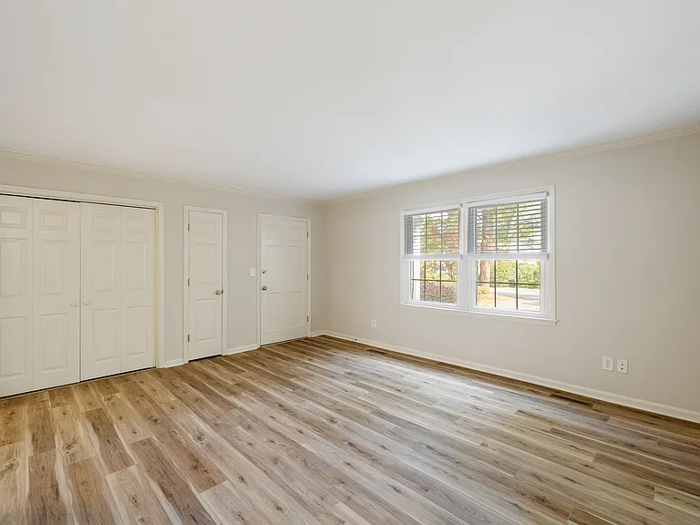 Living room; looking at front door, coat closet, laundry room/closet.