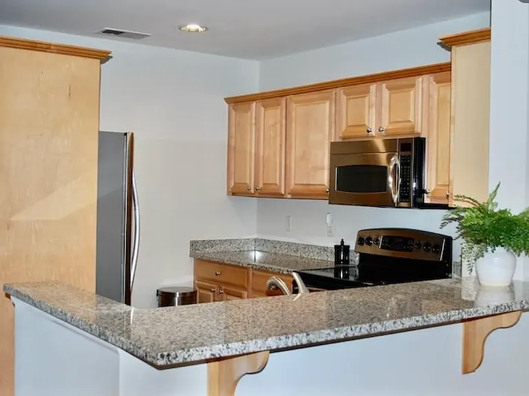 Modern kitchen with stainless steel appliances, including a new refrigerator. Granite counter tops.