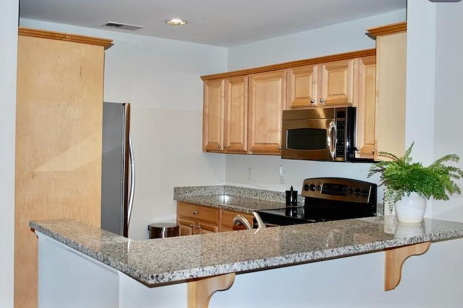 Modern kitchen with stainless steel appliances, including a new refrigerator. Granite counter tops.
