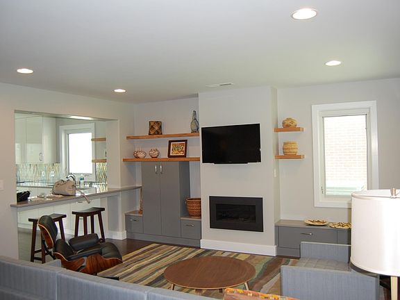 Living room with storage, flat screen tv, sofa and chair, counter seating.