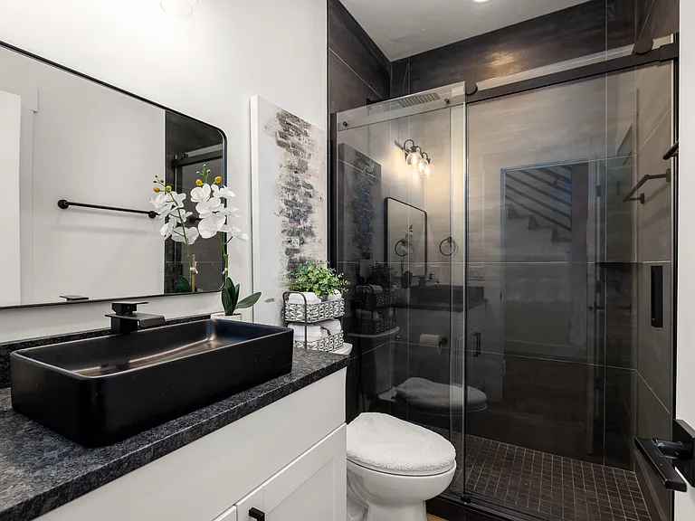 Stylish main-floor bathroom with a modern walk-in shower, sleek black finishes, and convenient access to the office or additional guest room.