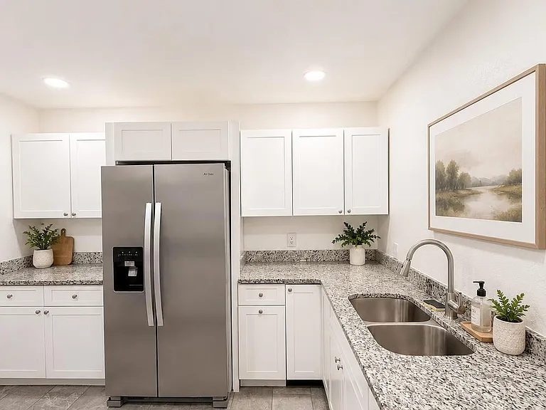 U-shaped kitchen with granite counters, stainless steel refrigerator, double-basin sink, and ample cabinet storage.