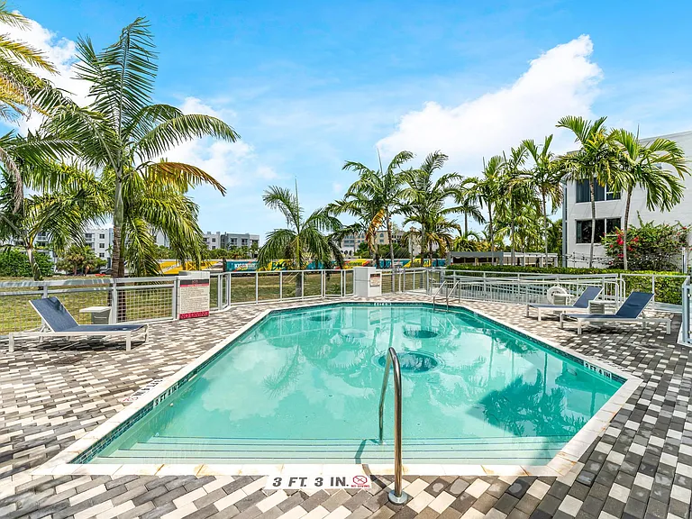 Pool Area with Lounge Chairs, Tile Decking, and Palm Tree Views in Courtyard Setting