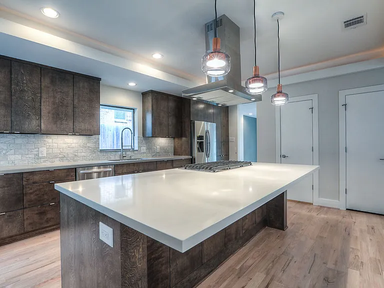 Alternate kitchen angle _ oversized island with seating, designer copper-trimmed pendant lights, and cove-lit tray ceiling