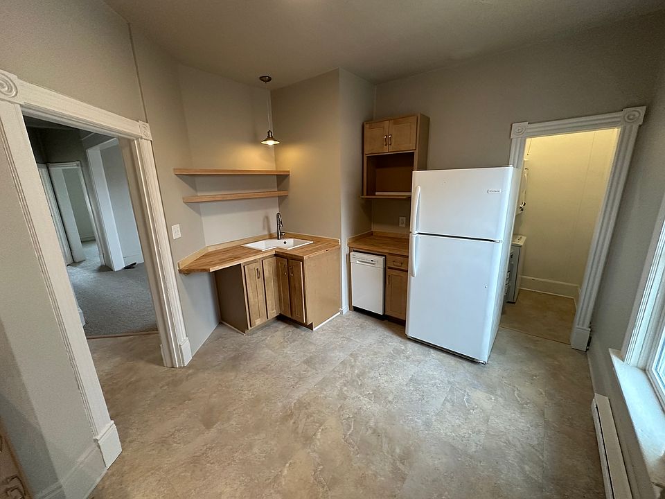 Kitchen sink, refrigerator, and dishwasher. Laundry room to the right. View to the left into living room.