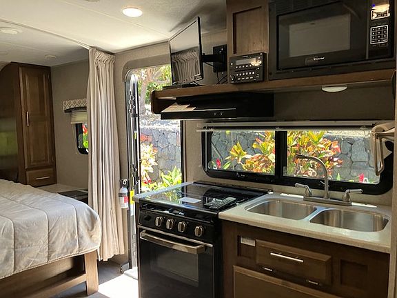 Kitchenette with 3-burner stove with oven, double sink, refrigerator with freezer.