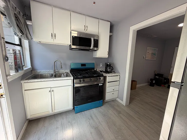 Compact kitchen with ample cabinetry, double-basin sink, gas range with microwave, and durable counters for easy meal prep.