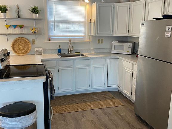 Kitchen with new sink and faucet, new countertops and freshly painted cabinets. Appliances include stove, refrigerator and microwave.