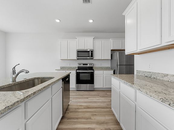 The kitchen features modern white cabinets and granite countertops