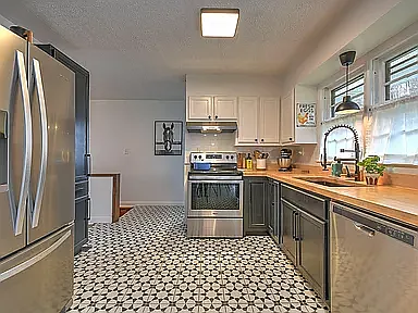 Mosaic tile and dark cabinets give an elevated energetic look to a spacious kitchen with butcher block counters.