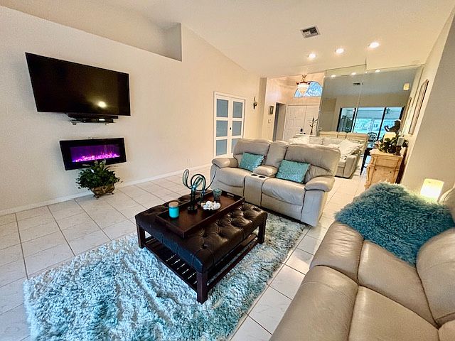Living room with electric fire place, cathedral ceilings, reclining sofa, sitting area, and Large TV with surround stereo sound bar