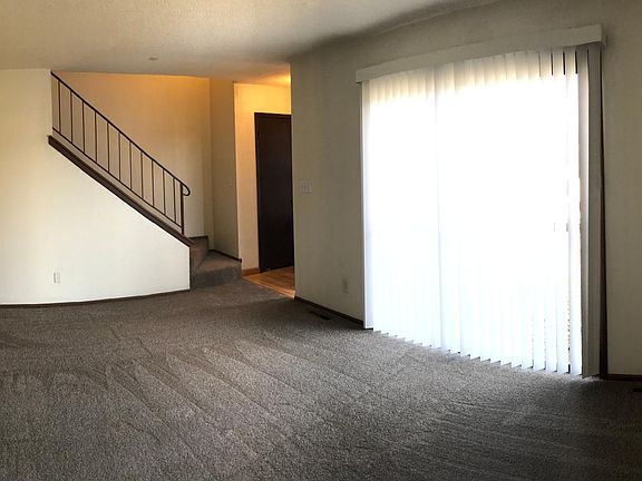 Spacious living room with patio doors looking out to front yard. There is a coat closet by the front door.
