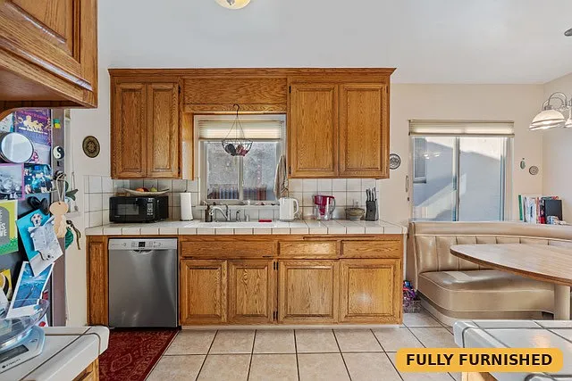 kitchen equipped with dishwasher, refrigerator/freezer, microwave, gas stove/oven, ventilation hood over stove and typical small appliances, serving dishes and flatware.