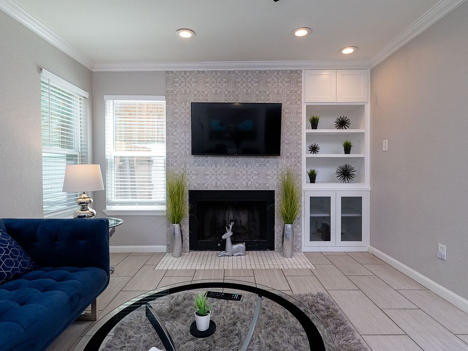 Spacious living room with couch, fireplace and flat screen TV with natural light.