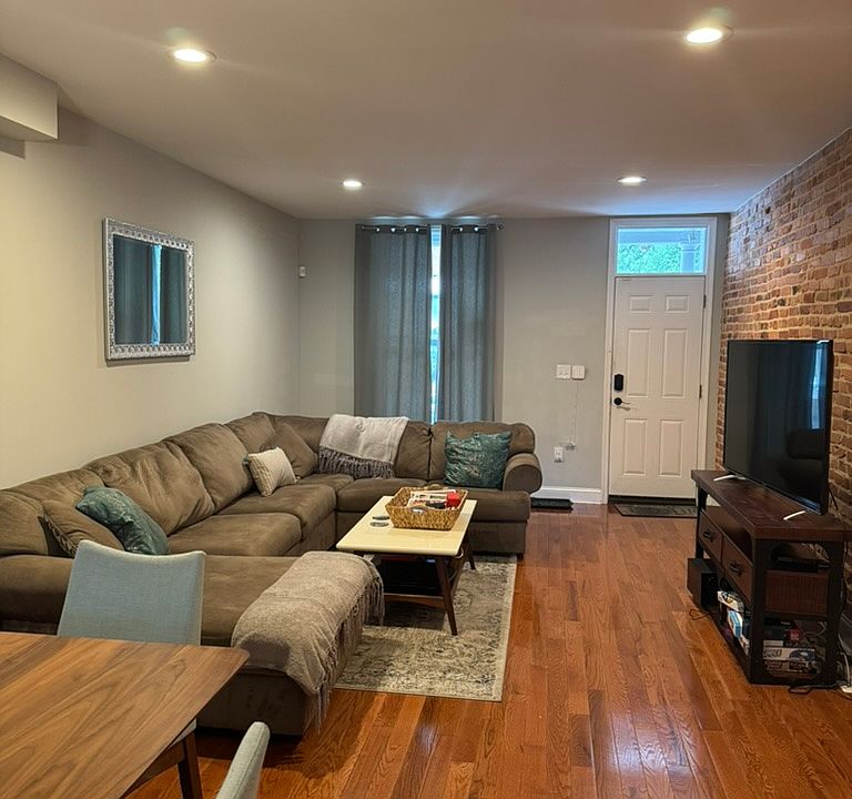 Shared living room furnished with large sectional, coffee table and tv