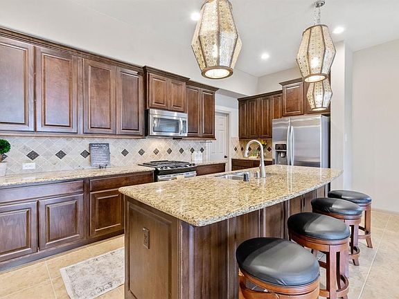Gourmet Chefâs kitchen with large granite island, upgraded pendant lighting, stainless steel appliances, and walk in pantry.