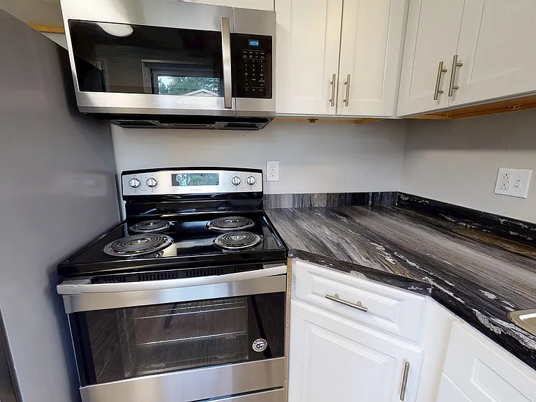 Whip up meals in style with The Hampshire's modern kitchen, featuring stainless steel appliances, white cabinetry, and black-fusion countertops.