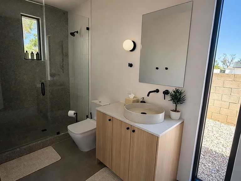Modern ensuite bathroom with a walk-in glass shower, vessel sink, and sleek matte black fixtures.