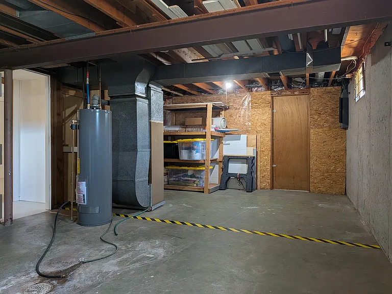 Basement room, looking back to staircase on left. Area beyond caution tape reserved for landlord materials storage and general access to breaker box