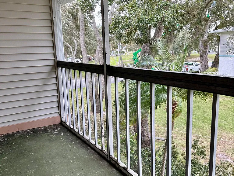 Screened porch overlooks green space with pond in background