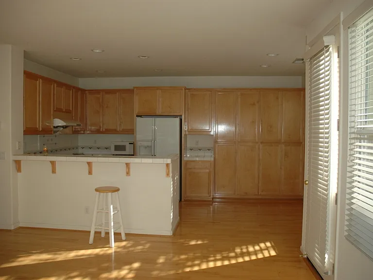 Bright kitchen features ample oak wood cabinetry, gas stove & oven, self-cleaning Pacific hood perfect for Asian cooking, and a breakfast bar. The adjoining dining area (right) boasts wall-to-wall windows framing unobstructed views of the backyard garden.