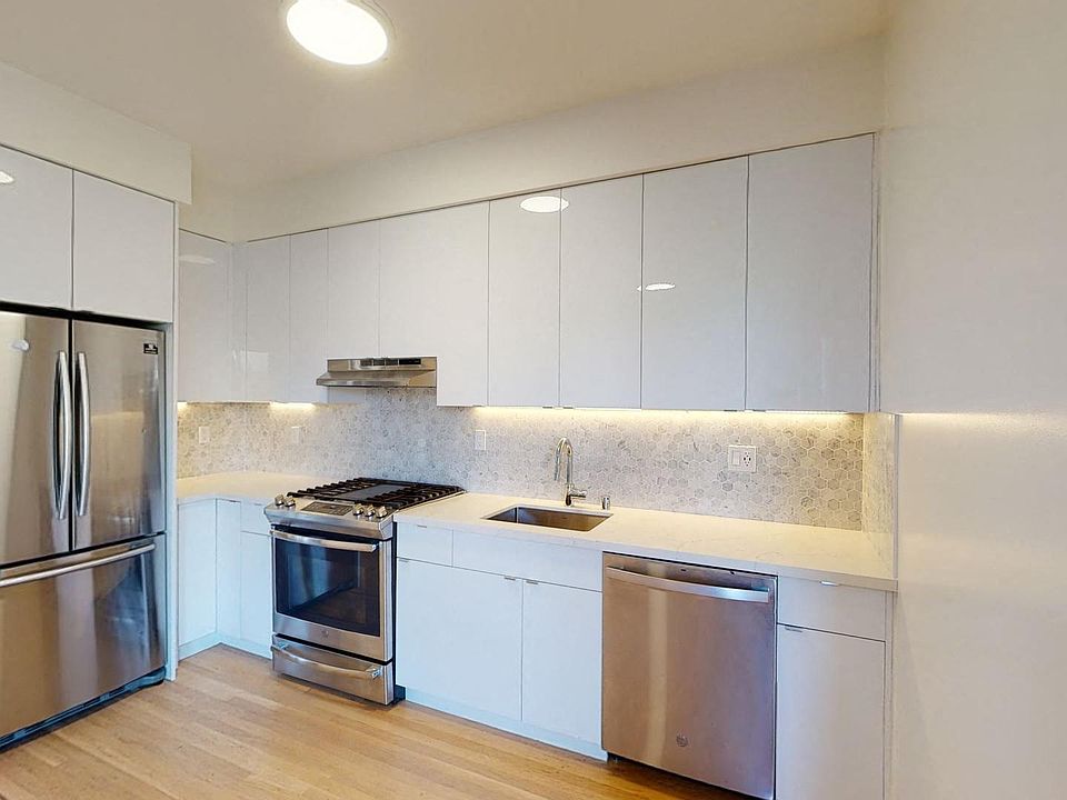 Kitchen with multiple cabinets, refrigerator, stove, range hood, and sink