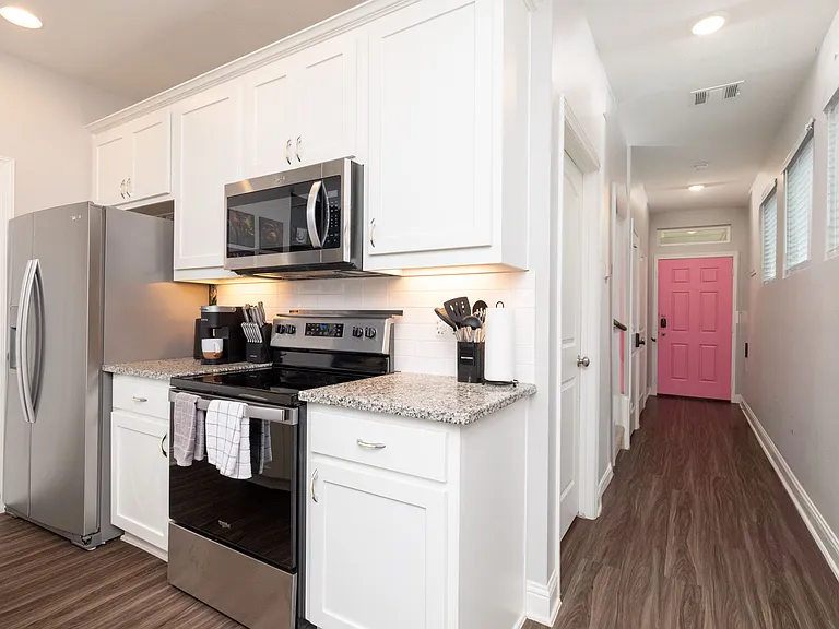 View of the fully stocked kitchen and hallway to the front door.