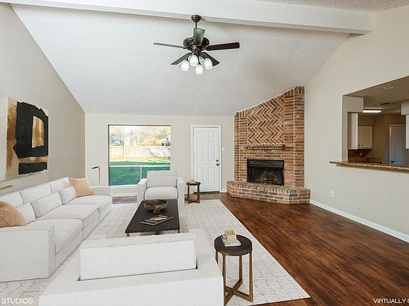 The den features raised ceilings, a cozy wood burn