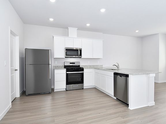 The kitchen has stainless steel appliances and plank flooring.