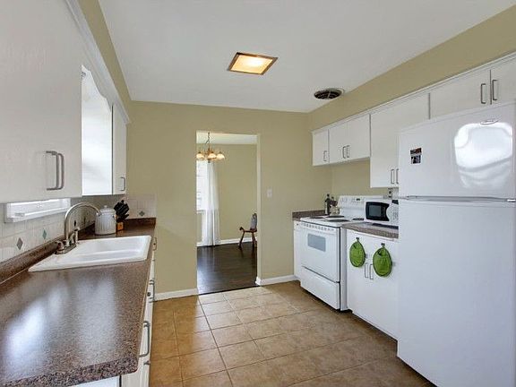 Spacious kitchen with tile floor, new counters and tile backsplash.