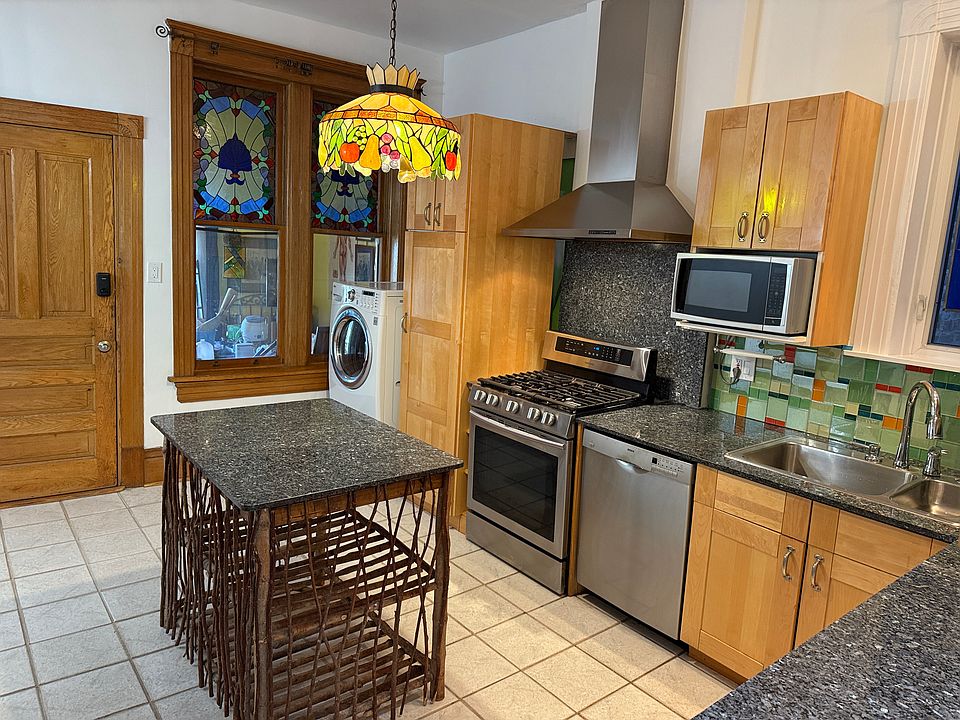 Kitchen island made of tree branches topped with blue galaxy granite like the rest of counters.