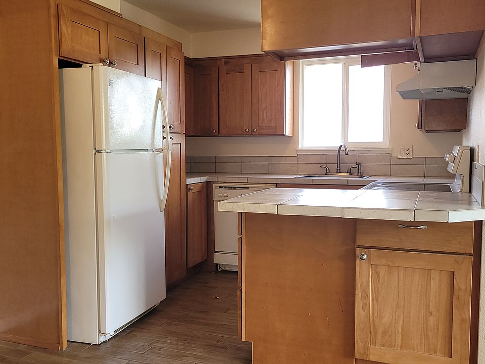 kitchen includes range, refrigerator, tile floor, tile counter tops, dishwasher, disposal, and new cabinets with ample storage space