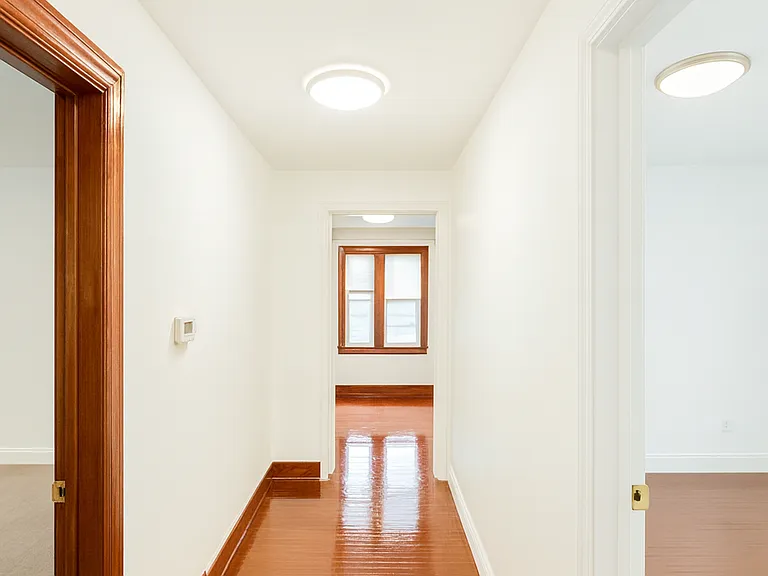 Bright and well-lit hallway connecting the front three bedrooms, creating an open and functional layout throughout the apartment. The kitchen is conveniently located in the center, with an additional private bedroom situated on the opposite side.