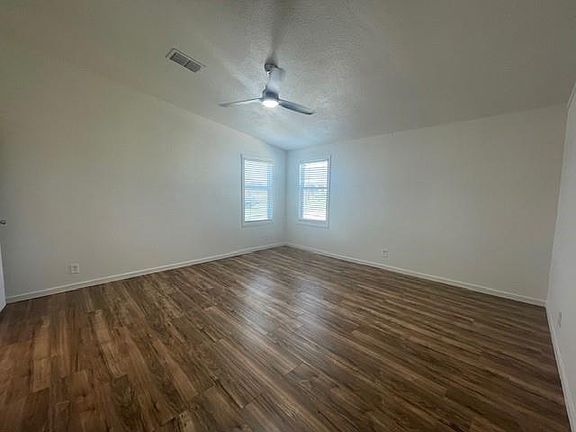 Unfurnished room featuring a textured ceiling, dark wood-style flooring, lofted ceiling, and ceiling fan