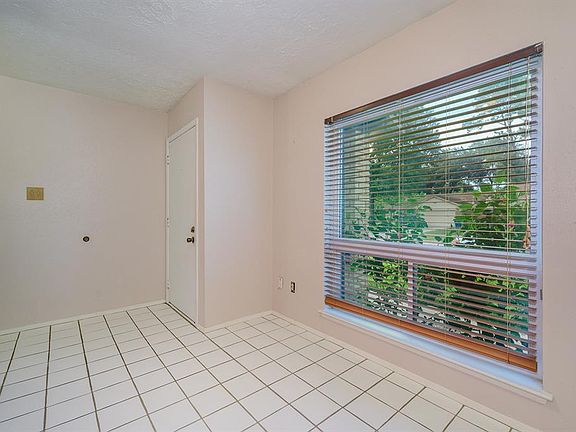 Tiled floor and large window with custom wood blinds in dining room.