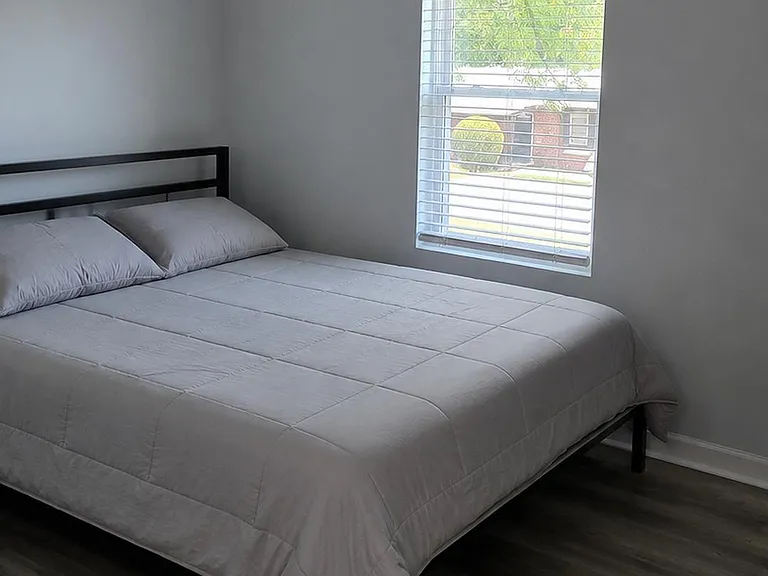 Bedroom with a full bed, ceiling fan, and a large window with blinds, plus durable wood-look flooring.