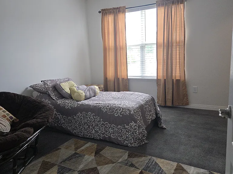Bedroom 2: Twin bed, dresser, walk-in closet, area rug, remote-controlled ceiling fan, curtains, chair