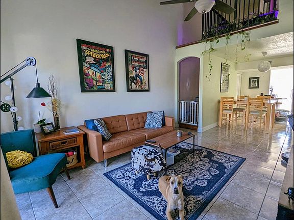 Large living room area with 2-story, vaulted ceiling, freshly painted, tile flooring.