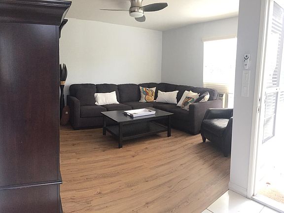 Spacious living room, recently installed LVT flooring. Ceiling fan and AC window unit.