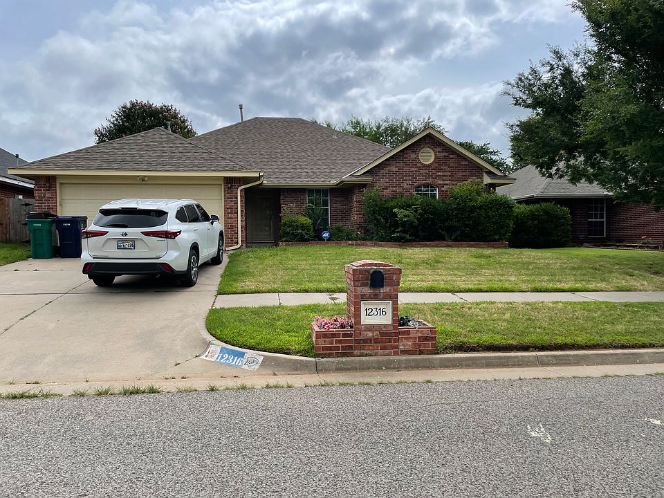 Photo of front of house, with 2 car garage. Northwest bedroom window is in middle of photo, Southwest bedroom window is on right, behind the hedge.