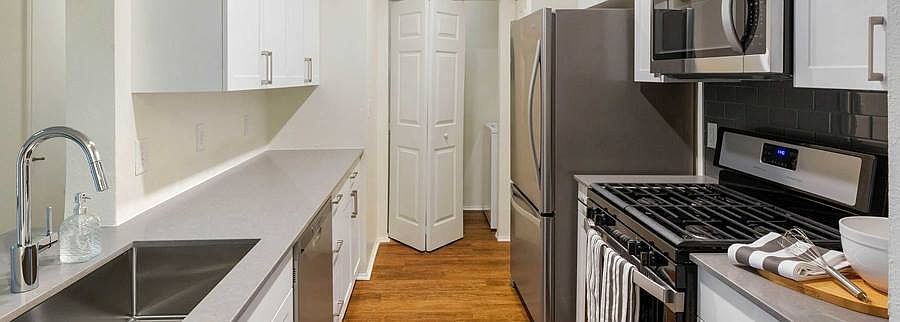 Finish Package II kitchen with white cabinetry, quartz countertops, stainless steel appliances, and hard surface flooring