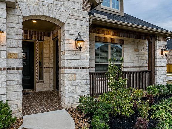 Covered front porch with brick flooring and beautiful carriage lighting.