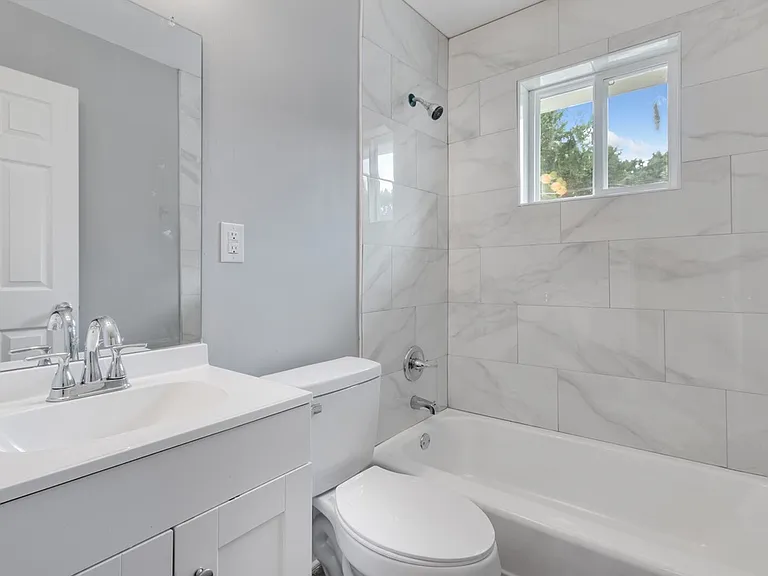Newly renovated bathroom includes floor-to-ceiling tile