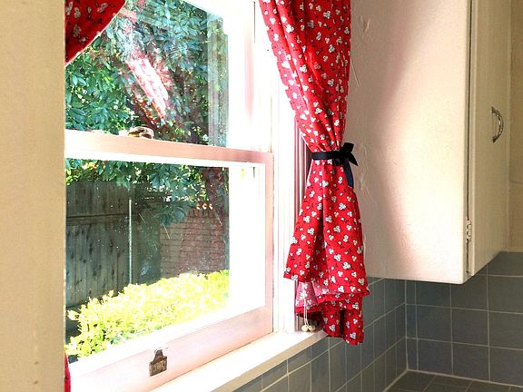 Custom made curtains frame the kitchen windows.