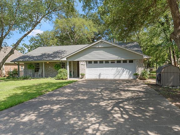 Single-story residence featuring a covered front porch, a two-car garage with panel windows, and a stone and siding exterior