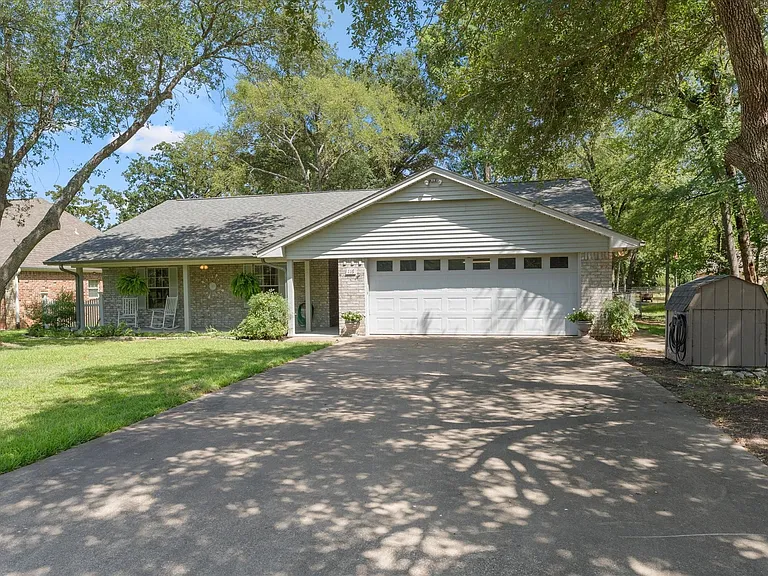 Single-story residence featuring a covered front porch, a two-car garage with panel windows, and a stone and siding exterior