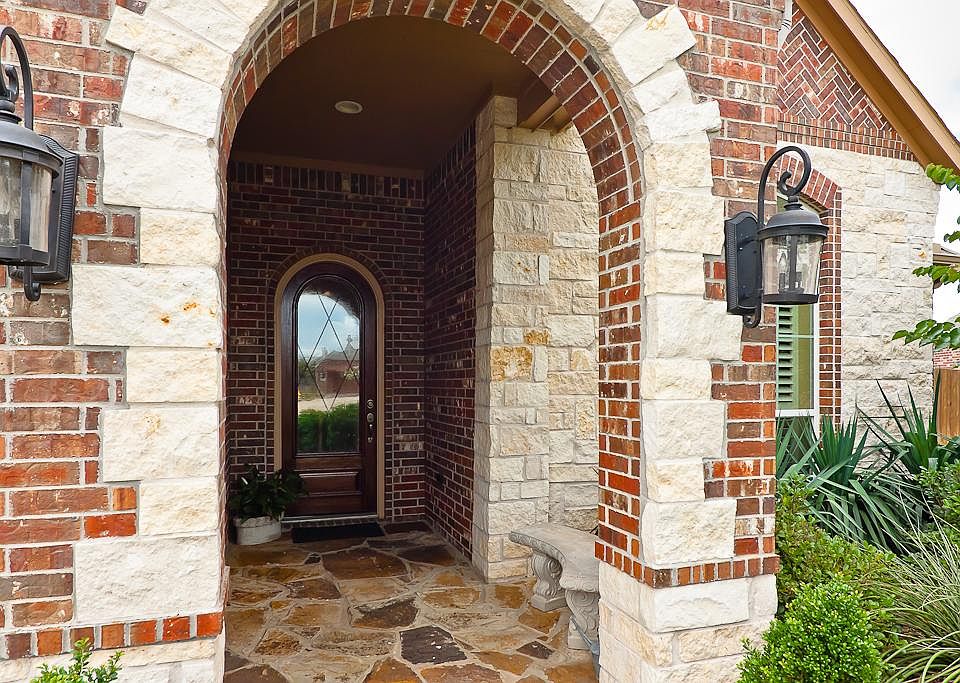 Charming front porch with a brick and stone lined arched opening includes a flagstone floor and rece