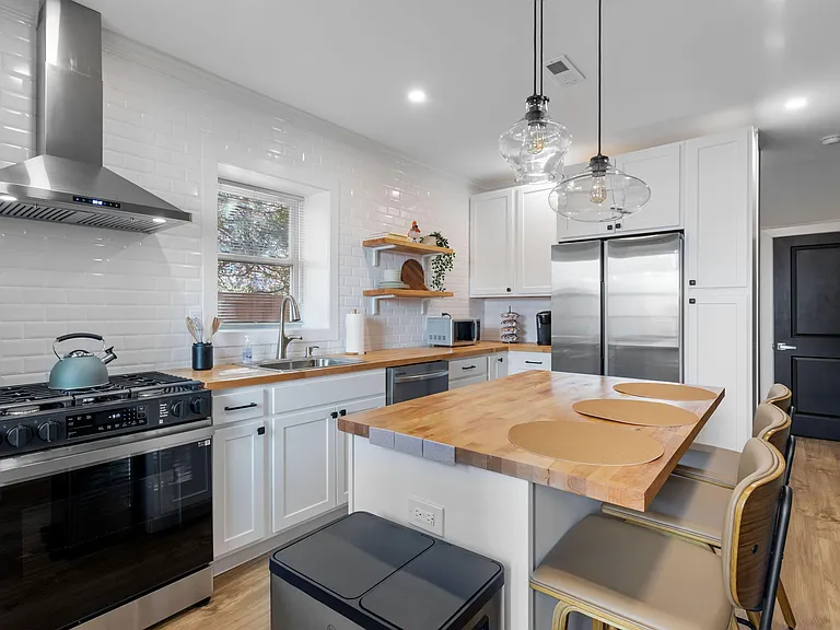 Updated kitchen with stainless appliances, gas range, butcher-block counters, and an island with bar seating.
