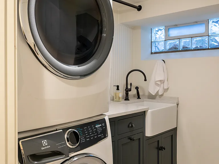 Basement Laundry features stackable laundry, custom cabinetry and a full sized farmhouse sink.
