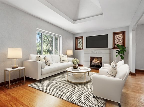The sunlit living room features a vaulted ceiling and a decorative fireplace.